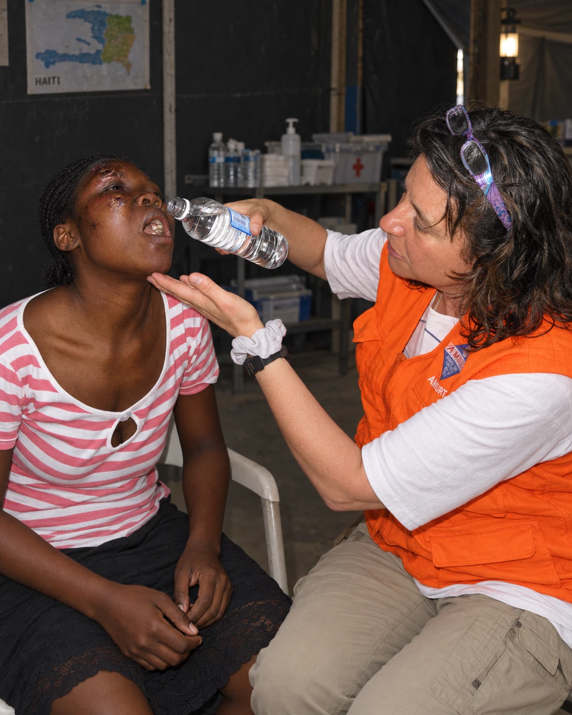 An AMURT relief worker helping a woman drink water in Haiti