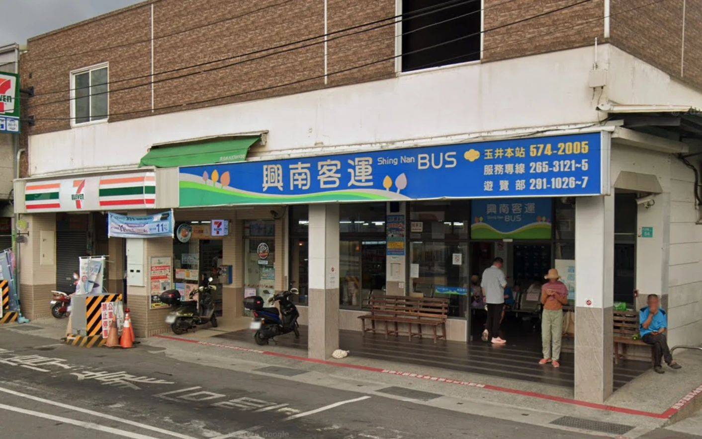 The Shing Nan Bus station in Yujing, with its blue sign, benches and a convenience store beside it